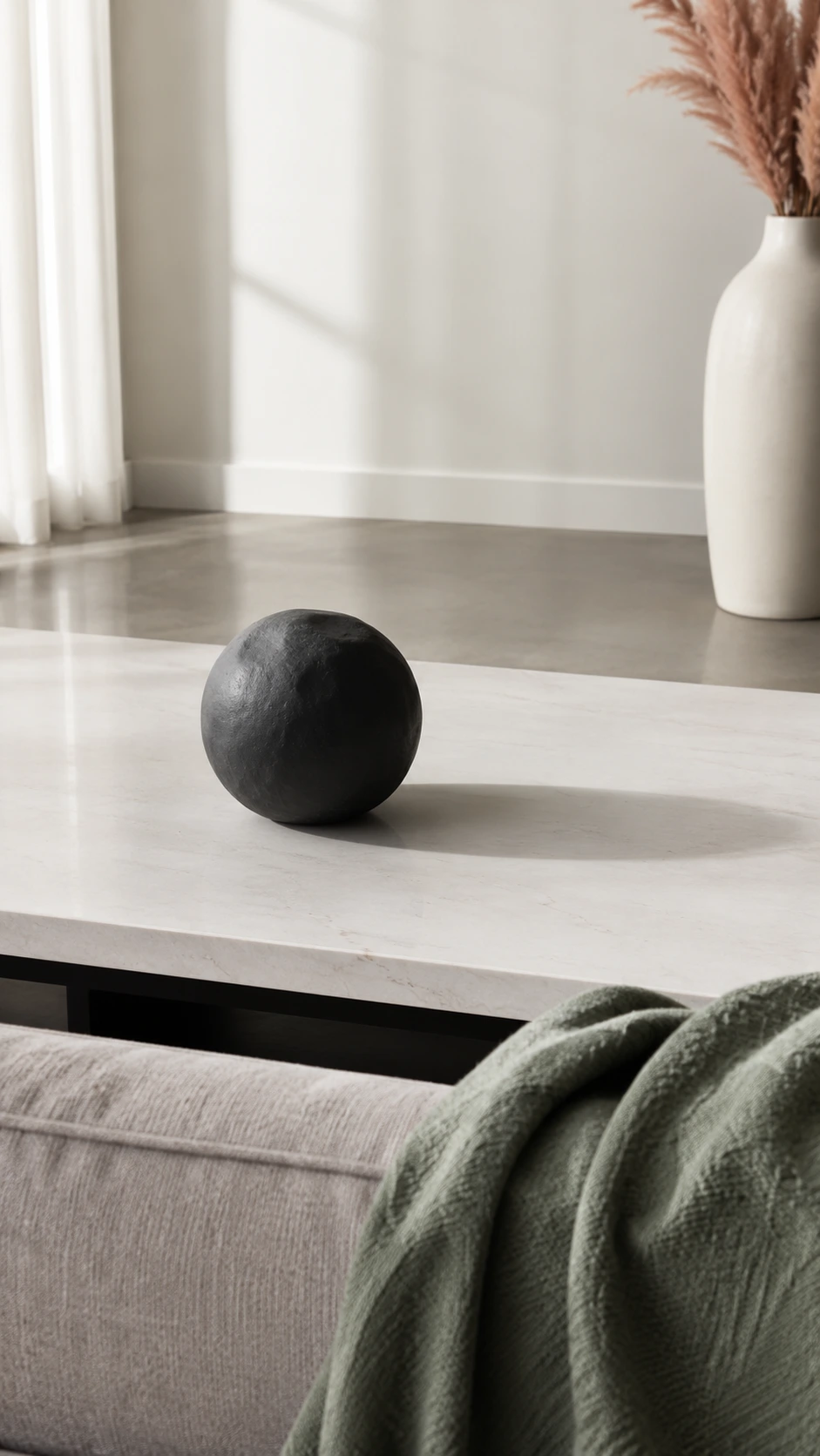 Low rectangular coffee table on polished concrete floor with a single statement object, styled in a bright modern living room with soft white walls and afternoon light