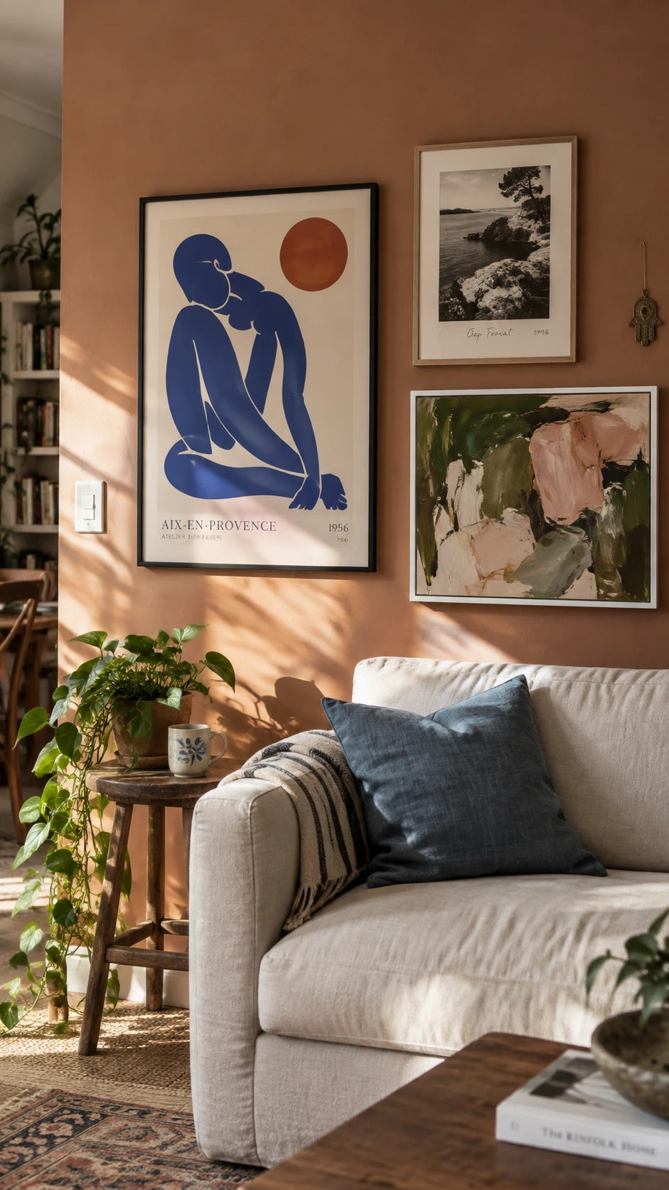 Curated gallery wall with bold, personality-driven artwork on warm terracotta wall in a well-designed Airbnb living room