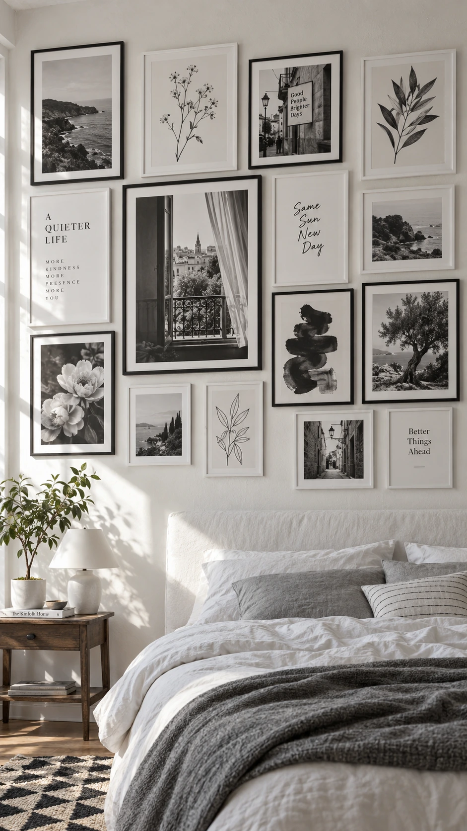 Black and white gallery wall with 12-15 mixed frames arranged above a bedroom headboard, styled against a warm white plaster-textured wall in natural daylight
