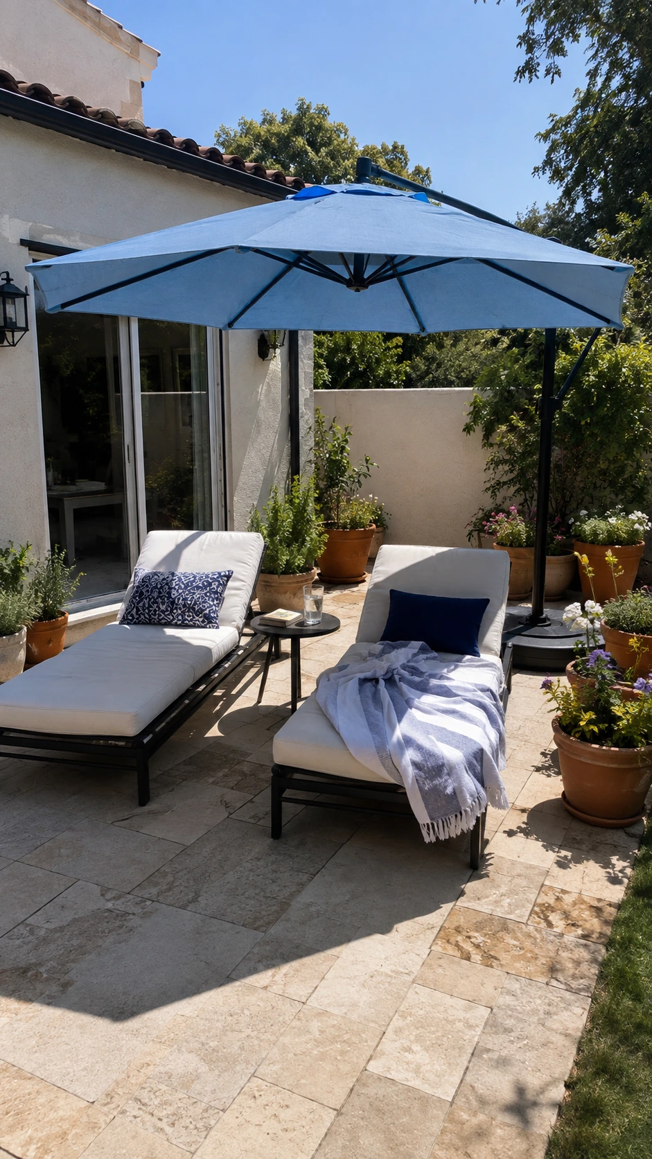 Blue cantilever umbrella shading two chaise lounges and a side table, showing patio shade ideas with the pole off the seating area