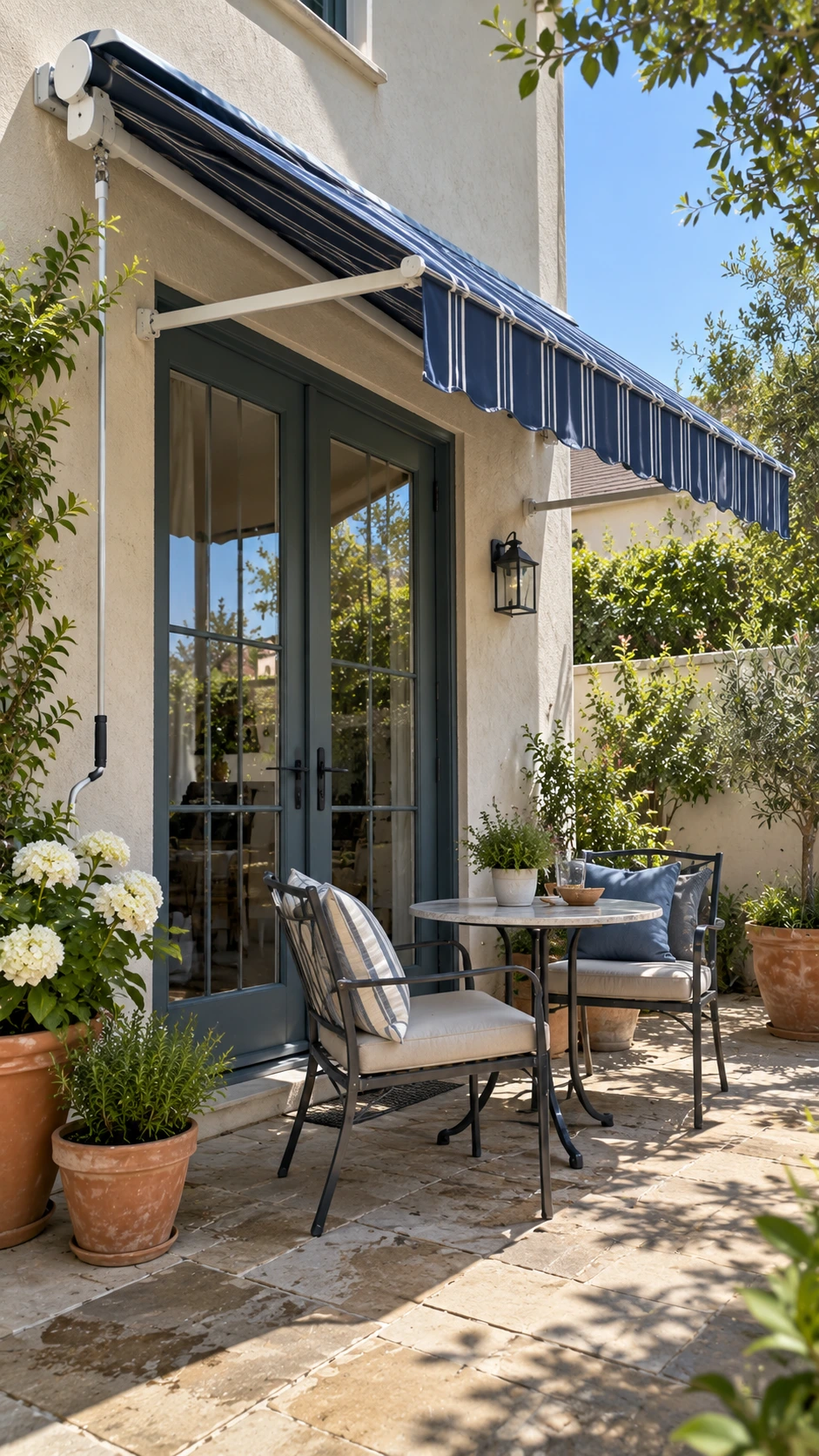 Patio Shade Ideas: deep blue striped retractable awning over a glass back door, shading the entry and small painted patio.